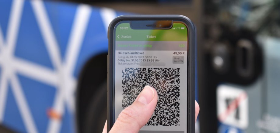 Finger auf einem Handydisplay mit der App im Hintergrund