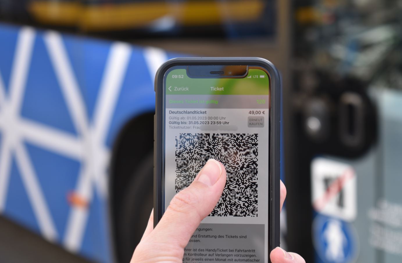 Finger auf einem Handydisplay mit der App im Hintergrund
